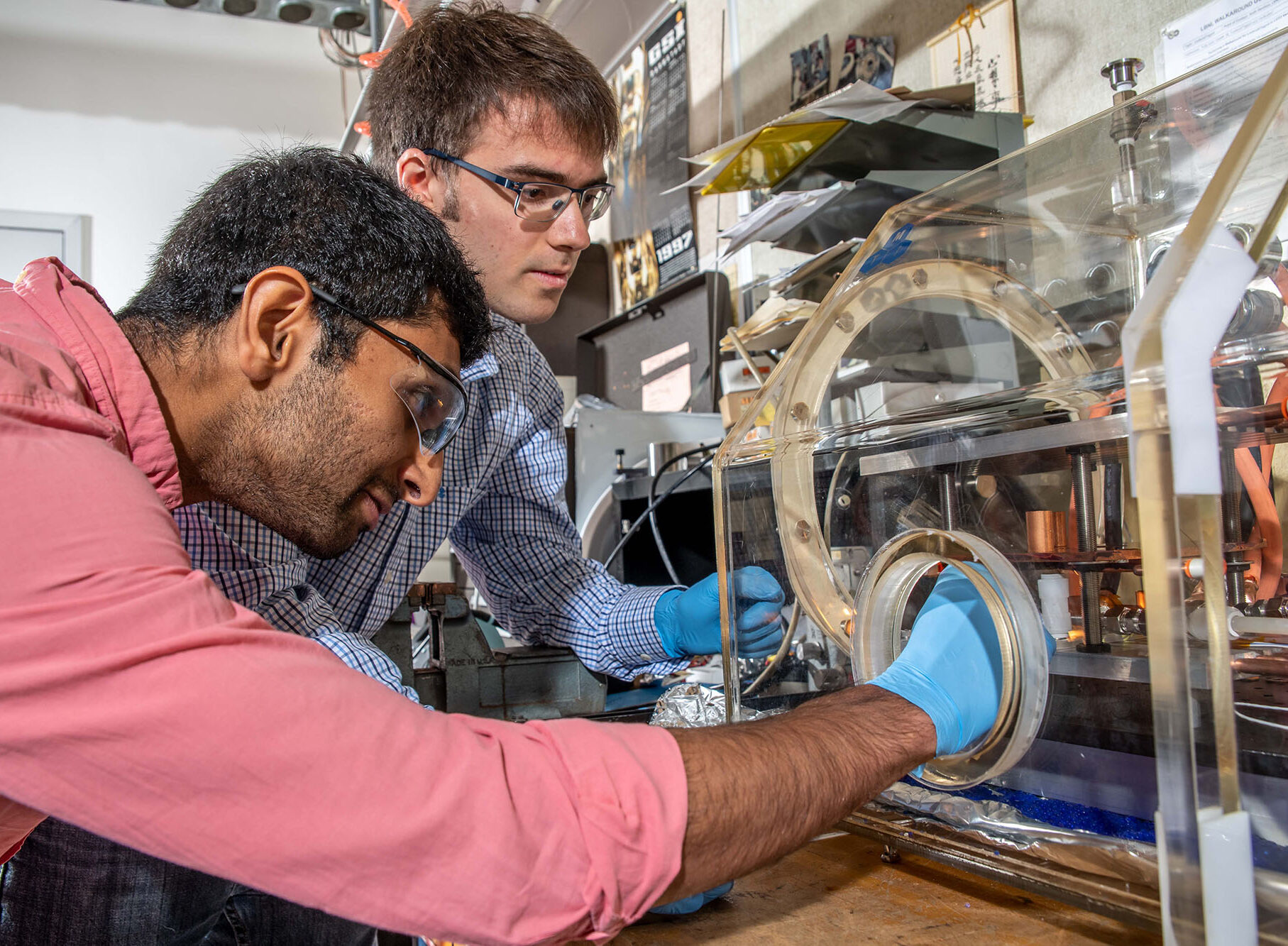 Two scientists in protective goggles working with experimental materials.