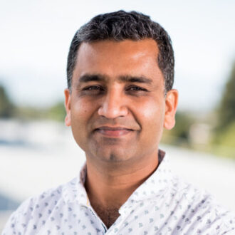 Vivek Mutalik, a person with short dark hair wearing a patterned white shirt, photographed outdoors.