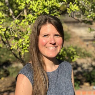 Portrait of Allison Pieja, a person with long brown hair wearing a dark blue top, smiling.