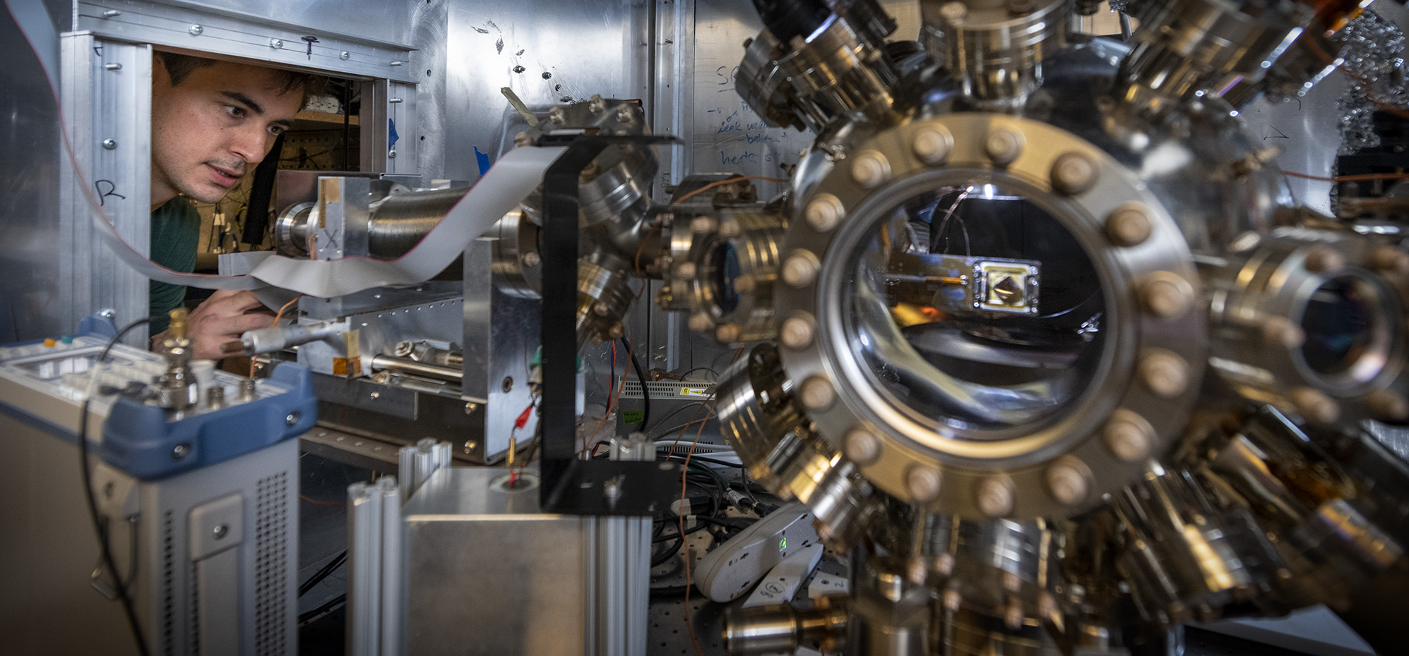 Graduate student Ben Saarel adjusts the settings on a vacuum apparatus used to make trapped ion qubits on the UC Berkeley campus.