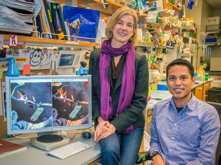 Man and woman posing next to computer monitor